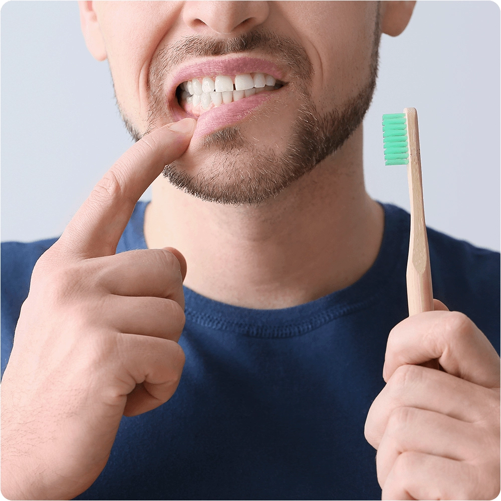 Person showing tooth with toothbrush in hand