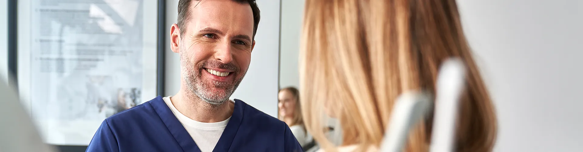 Smiling dentist talking to a patient during a consultation in a modern dental office.