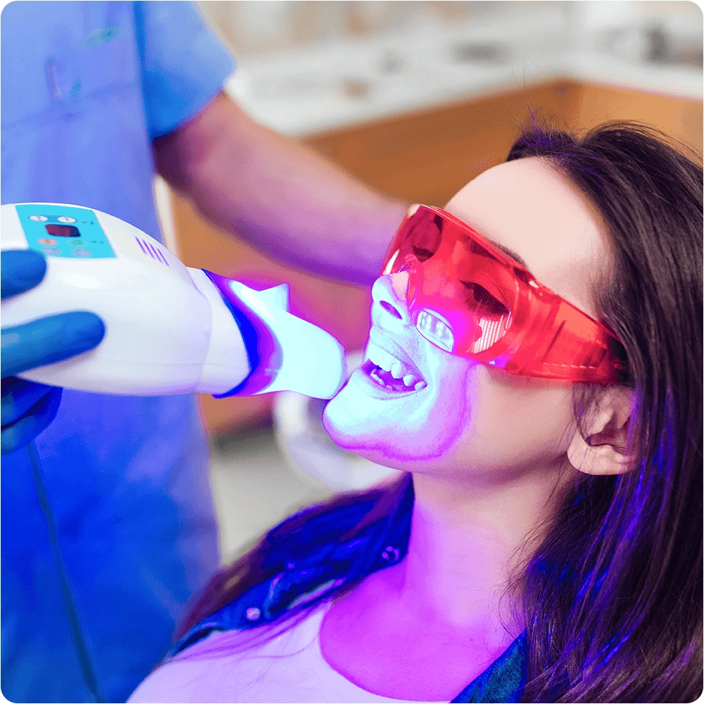 Dentist applying blue light whitening to patient