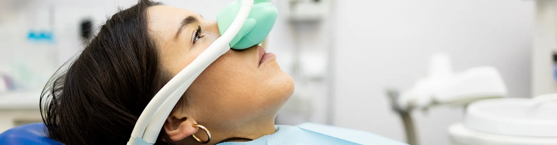 Patient wearing a sedation mask in a dental chair, illustrating the use of nitrous oxide for relaxed dental treatment.