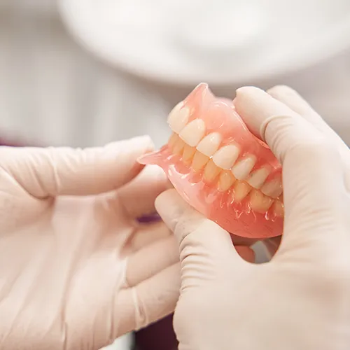 gloved hands holding a set of dentures