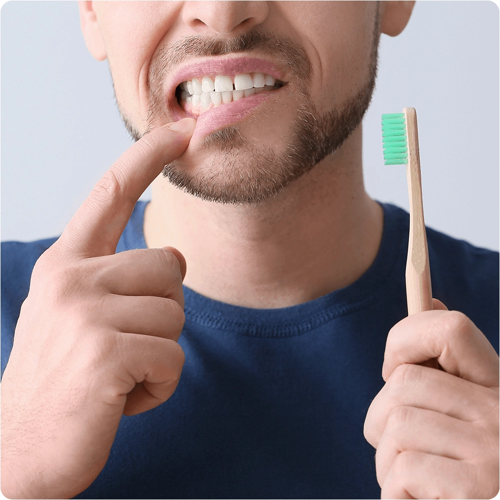 Person showing tooth with toothbrush in hand